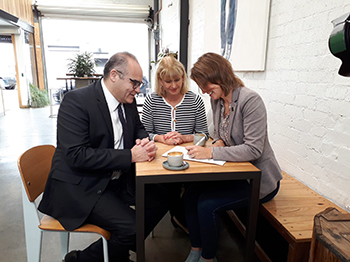 Image, left to right: Minister for Small Business, Adem Somyurek, seated with Victorian Small Business Commissioner, Judy O'Connell and City of Yarra Mayor, Danae Bosler - one of the first councils to sign the Small Business Friendly Council Charter at Maker Coffee in Richmond.